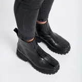 Botas cortas color marrón de cuero vacuno con suela track negra de goma. Presentan cierre lateral con cremallera YKK y puntera cuadrada.