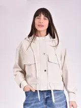 Chaqueta color crudo con capucha, cierre con botones a presión, bolsillos delanteros con solapa y cordón ajustable en la cintura.