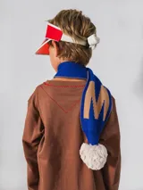 Bufanda azul y marrón con pompones grises, confeccionada en algodón.