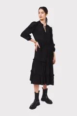 Vestido midi negro con escote en V, mangas largas con volados en los hombros, cintura con lazo ajustable y falda escalonada con volados.