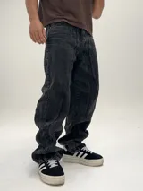 Pantalón de jean negro con efecto lavado, corte amplio tipo baggy y costuras verticales en el frente.