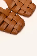 Sandalias franciscanas rojas de cuero con tiras entretejidas y hebilla lateral.