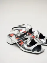Sandalias de cuero charol color borgoña con tiras finas, taco cuadrado bajo y cierre con hebilla en el tobillo. Interior con estampado del logo de la marca en color naranja.