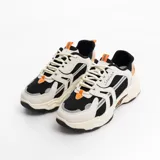 Zapatillas deportivas de mujer en color negro y blanco, con detalles en naranja y diseño moderno.