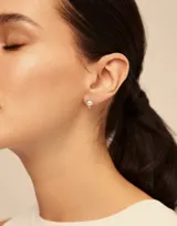 Aro piercing dorado con perla blanca en el centro.