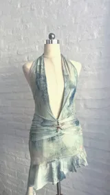 Minivestido con estampado abstracto en tonos celeste, verde y blanco. Escote halter con lazos en la nuca, espalda descubierta y falda con volados.