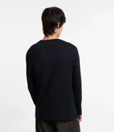 Remera negra de algodón, corte slim, cuello redondo, mangas largas y aberturas triangulares en los hombros.