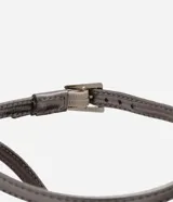 Zapato de tacón color gris con punta fina, tira fina con hebilla en el tobillo y detalle de nudo con strass.