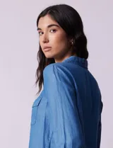 Camisa celeste de lyocell, marca Zac & Rachel. Cuello con solapa, abertura central con botones y bolsillos delanteros.