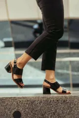 Sandalia de tacón con diseño negro, abierta en la parte delantera y con hebilla ajustable en el tobillo.