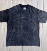 Remera negra con efecto gastado, corte holgado y estampa en la espalda con montañas y la palabra "Mountain" en blanco.