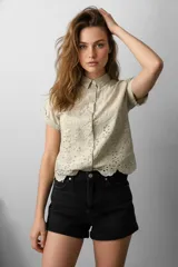 Camisa color beige con bordado floral, de corte holgado, con cuello camisero y cierre frontal con botones.