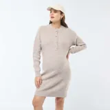 Vestido corto color beige, tipo sweater, de tejido de punto con cuello redondo y manga larga. Presenta una abertura frontal con botones para facilitar la lactancia.