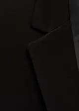 Chaqueta negra con cuello de pico con solapa y cierre de botón en la parte delantera.