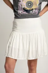 Minifalda blanca de lino y viscosa, con cintura alta y volado con calado en el ruedo.