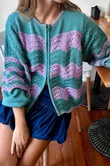 Campera de tejido de punto con cierre frontal doble, presentando un patrón de ondas en colores verde azulado y lila.