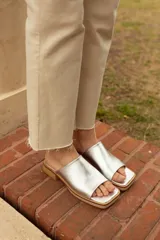 Sandalias plateadas con base de madera clara y tira ancha sobre el empeine.