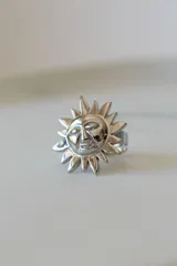 Anillo plateado con forma de sol con rostro, ajustable entre 16mm y 19mm. Fabricado en acero quirúrgico hipoalergénico.