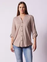 Blusa Ninety color beige con textura, cuello base con escote en V y abertura central con botones. Tiene un bolsillo en el pecho y mangas 3/4 regulables con presilla y botón.