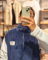 Campera de peluche azul con mangas blancas, cierre frontal y cuello alto.