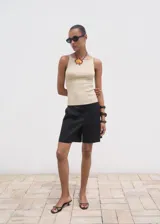 Top sin mangas de tejido de punto fino color beige claro, con cuello barco y tirantes finos, de diseño entallado.