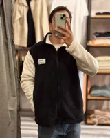 Campera de peluche negra con mangas blancas, cierre frontal y cuello alto.