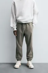Pantalón jogger negro de corte slim fit, confeccionado en tejido de algodón con cintura elástica ajustable con cordón, bolsillos frontales y traseros de vivo, y bajo con puño elástico.