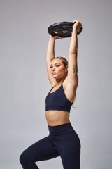 Top deportivo color beige con banda inferior azul y tirantes finos azul marino. Espalda cruzada con doble tira.