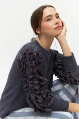 Remera negra de punto con mangas largas abullonadas con volantes.