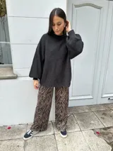 Sweater tejido color gris oscuro, de corte holgado, cuello redondo y mangas largas con puños ajustados.