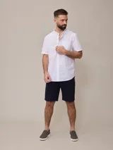 Camisa de algodón blanca de manga corta, con cuello abotonado y botones frontales.