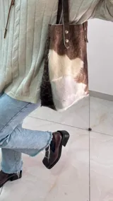 Bolso tote de cuero color marrón oscuro con doble asa larga de cuero y remaches metálicos.