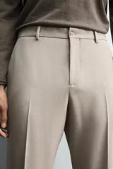 Pantalón de vestir color beige, corte slim fit, confeccionado en tejido con viscosa. Cuenta con bolsillos frontales y traseros de doble vivo con botón. Cierre frontal con cremallera y botón.