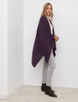 Ruana de tejido suave color morado oscuro, con cuello redondo y corte amplio tipo capa.