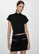 Minifalda negra de tejido de punto fino con tiro medio, corte recto, dos bolsillos de parche frontales y detalle en contraste en los bordes.