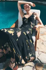 Vestido largo negro con estampado floral en tonos naranja y blanco, escote en V y breteles finos.