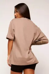 Remera color beige con estampado de texto en el frente, corte amplio y mangas cortas.