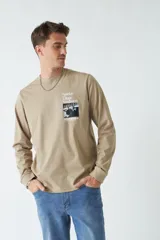 Remera de manga larga blanca con cuello redondo y estampado frontal con imagen de un pianista y texto en color celeste.