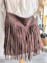 Bandolera marrón con flecos largos y detalles de ojales metálicos.