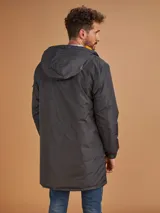 Abrigo largo color gris oscuro con capucha y forro naranja, cuenta con múltiples bolsillos.