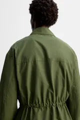 Parka verde militar de tejido técnico ligero, corte relaxed fit, cuello solapa y manga larga. Tiene cuatro bolsillos de plastrón con solapa en el delantero, cintura ajustable en el interior y cierre frontal con cremallera oculta por solapa con botones a presión.