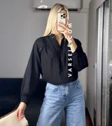 Camisa blanca de mangas largas con puños abullonados y detalles de encaje en cuello, mangas y ruedo.
