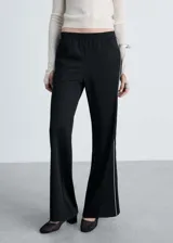 Pantalón negro de tiro medio con cintura elástica, corte recto y detalle de rayas blancas en los laterales. Estilo jogger.