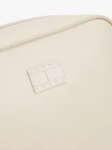 Bandolera Tommy Jeans color crema, de forma rectangular y correa ajustable. Presenta el logo de la marca en relieve en el frente.