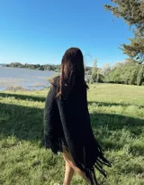 Ruana tejida a mano en lana Merino hilado grueso, con diseño en V y flecos.