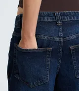 Pantalón de jean de mujer, modelo wide leg, con cintura baja tradicional, cierre por botón metálico y cremallera, y bolsillos curvos delanteros y traseros.