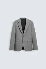 Blazer gris de corte recto, confeccionado en tejido con viscosa. Tiene cuello con solapas de muesca, manga larga con puño abotonado, bolsillo de vivo en el pecho, bolsillos de parche en la cadera y aberturas en la espalda. El cierre es con botonadura frontal.