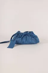Cartera sobre azul de cuero con frunces y pespuntes diagonales.