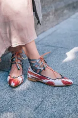 Botines con estampado de lenguas mallorquinas en color teja, con pieza de piel gris antracita en el tobillo y cordones de algodón con borlas de piel. Incluyen plantilla de piel y plantilla extra de lana intercambiable.