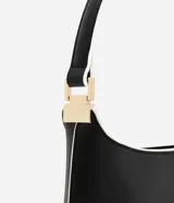 Cartera baguette mediana de cuero sintético color negro, con recortes geométricos en blanco en el frente y asa corta con detalle metálico.